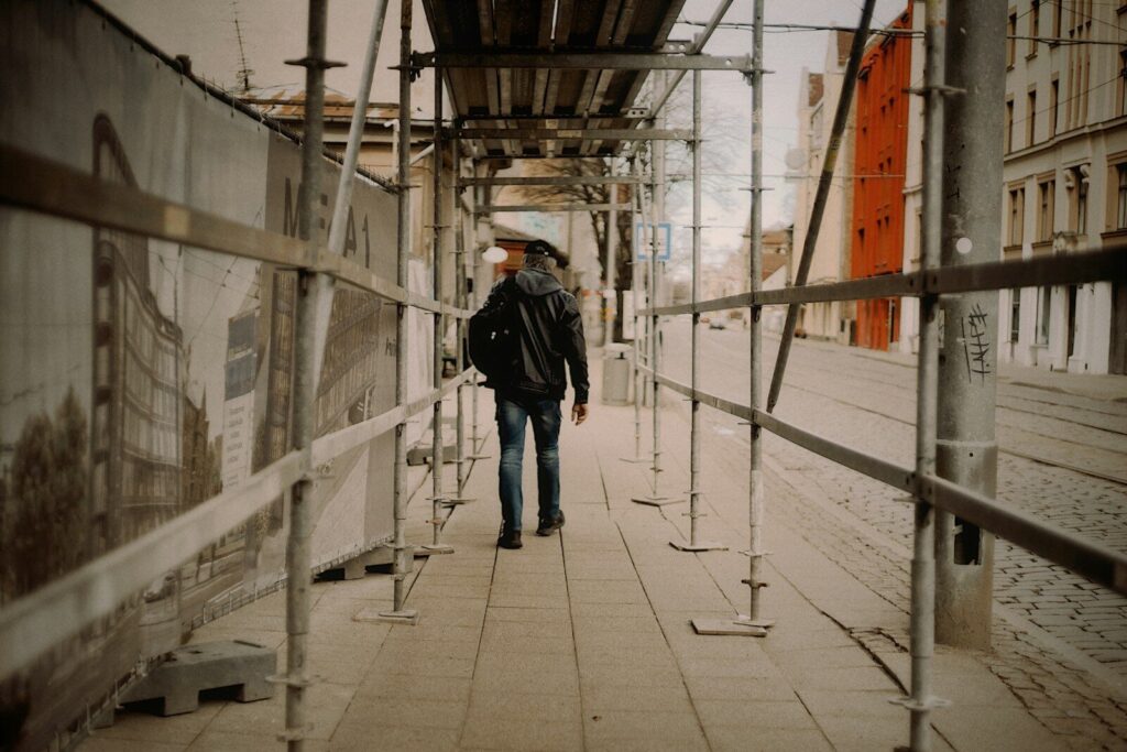 Person walks through scaffolding on city street.