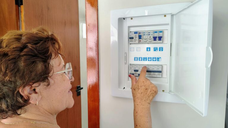 A senior woman is adjusting an electrical fuse panel indoors, demonstrating home safety.